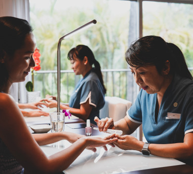 woman enjoying nail file manicure in spa