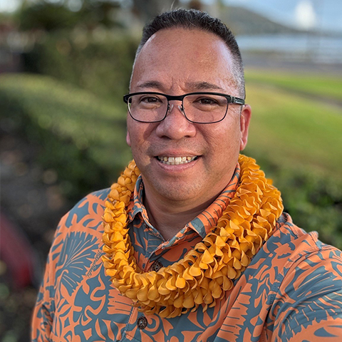 a man wearing floral shirt standing in front of grass