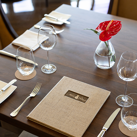 a dining table with cutlery, glasses and menu on it